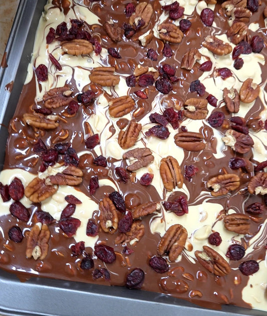 Artisan chocolate bark from Chocolates Sero, handcrafted in Guatemala. Features swirled layers of white and dark chocolate topped with nuts and dried cranberries — a festive, flavor-rich treat ideal for gifting and seasonal campaigns.